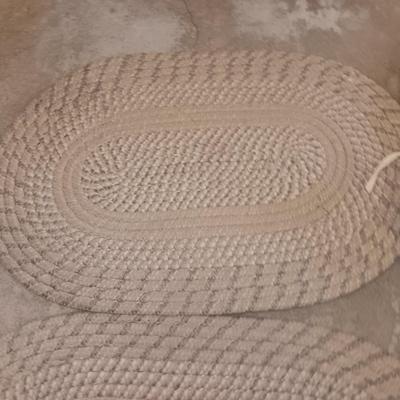 Two woven throw rugs and three white seat / chair cushions
