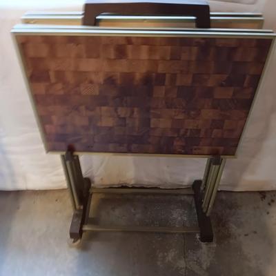 Two brown metal folding chairs and a set of 4 retro TV trays on organizing / storage cart.