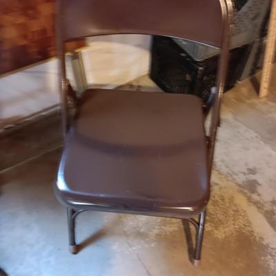 Two brown metal folding chairs and a set of 4 retro TV trays on organizing / storage cart.