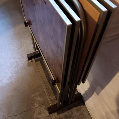 Two brown metal folding chairs and a set of 4 retro TV trays on organizing / storage cart.