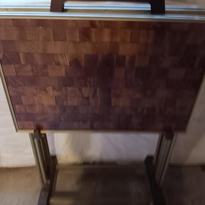 Two brown metal folding chairs and a set of 4 retro TV trays on organizing / storage cart.