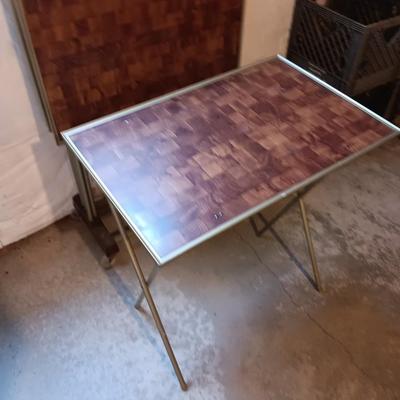 Two brown metal folding chairs and a set of 4 retro TV trays on organizing / storage cart.
