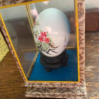 Vintage hand painted Chinese egg in a glass display case