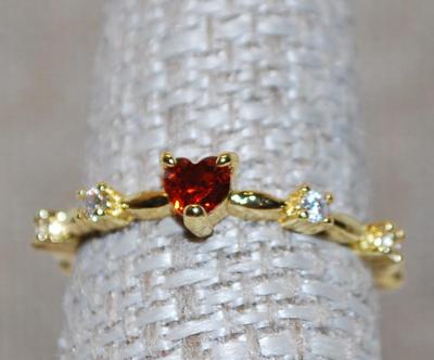 Size 8 Single Red Heart Shaped Stone Ring with Side Accents on a Gold Tone Band (1.5g)
