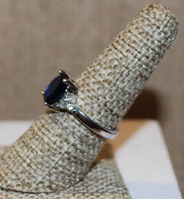 Size 8 Deep Blue Oval Center Stone Ring with 3 Clear Stones Side Accents on a Silver Tone Band (2.9g)