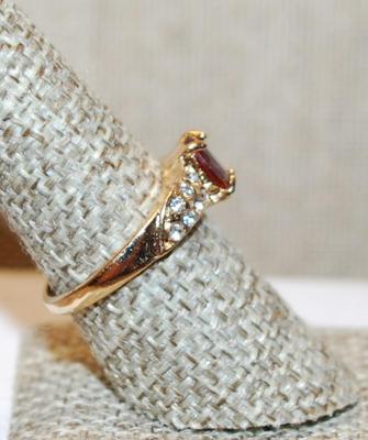 Size 8 Cranberry Red Oval Cut Stone Ring with 7 Clear Stones Each Side Accents on a Gold Tone Band (2.8g)