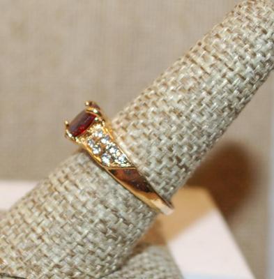 Size 8 Cranberry Red Oval Cut Stone Ring with 7 Clear Stones Each Side Accents on a Gold Tone Band (2.8g)