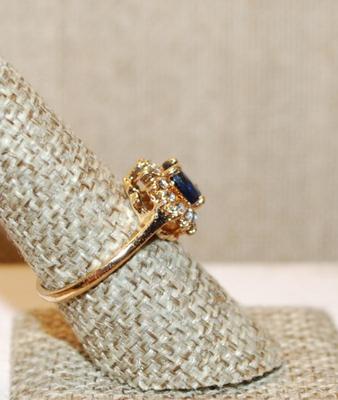 Size 8 Deep Blue Oval Cut Stone Ring with a Full Surround of Clear Stones on a Gold Tone Band (2.8g)