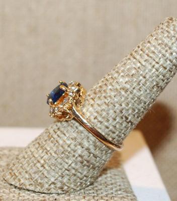 Size 8 Deep Blue Oval Cut Stone Ring with a Full Surround of Clear Stones on a Gold Tone Band (2.8g)