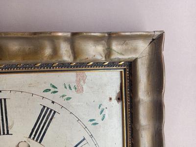Wooden face clock framed in an art deco gold frame