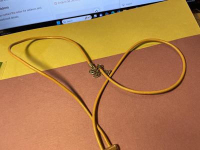 Modern Day Bolo Tie Gold-tone Necklace on a Beige/Creme Color Cord in VG Preowned Condition.