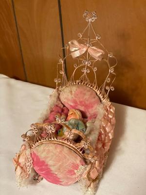 Small plastic doll with moveable limbs and eyes with pink bed