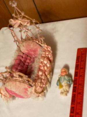 Small plastic doll with moveable limbs and eyes with pink bed