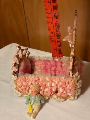 Small plastic doll with moveable limbs and eyes with pink bed