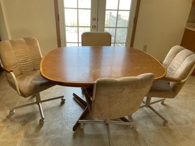 Oval oak dining room table with four rolling chairs