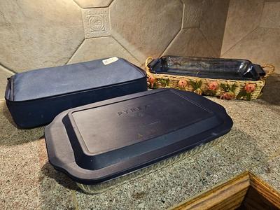 Two Glass Pyrex cake pan with lid and carry case and pyrex pan in basket