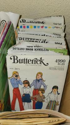 Box of sewing patterns, Singer sewing machine attachments, and assortment of other sewing needs