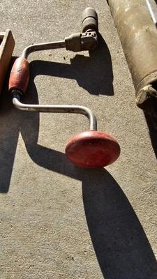 Vintage wood handled drill with drill bits and an old grease gun
