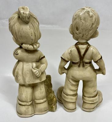 Sale Photo Thumbnail #562: This vintage figurine set features a little boy and girl with two empty pockets and a dog, all made of ceramic with a beautiful gold finish. The set is perfect for collectors of vintage children's items and is sure to add a touch of nostalgia to any decor