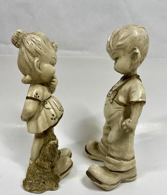 Sale Photo Thumbnail #561: This vintage figurine set features a little boy and girl with two empty pockets and a dog, all made of ceramic with a beautiful gold finish. The set is perfect for collectors of vintage children's items and is sure to add a touch of nostalgia to any decor