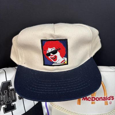 LOT 150: Vintage Ronald Mcdonald T-Shirt (qty 3, xl, xl, l), Hats (3) and a Lidded Plastic Coffee Mug