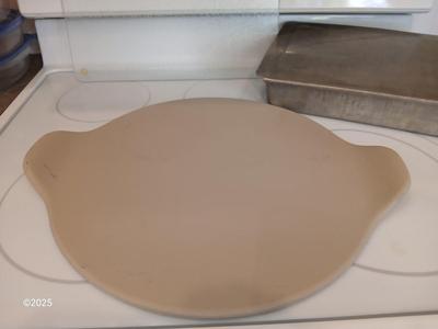 Pampered Chef 15 inch handled pizza stone with glass cutting board and a lidded metal cake pan