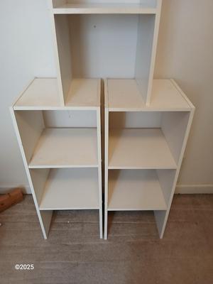 Three narrow white cubby shelves
