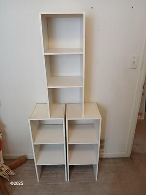 Three narrow white cubby shelves