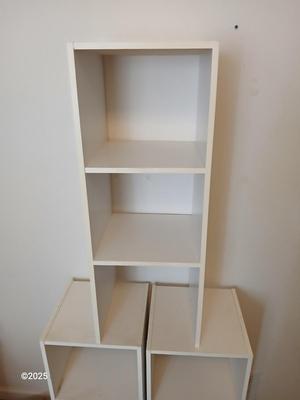 Three narrow white cubby shelves