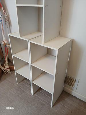 Three narrow white cubby shelves