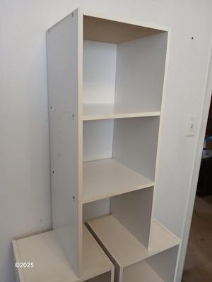Three narrow white cubby shelves