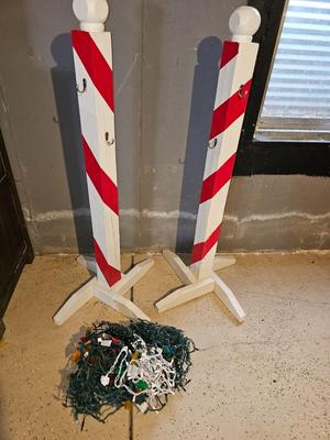 Two candy cane stripe posts with hooks and a box of Christmas light strands