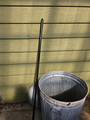 Galvanized metal trash can with lid and a push broom