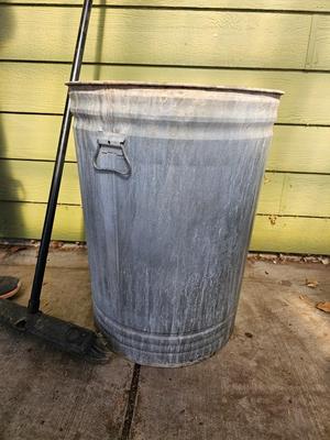 Galvanized metal trash can with lid and a push broom