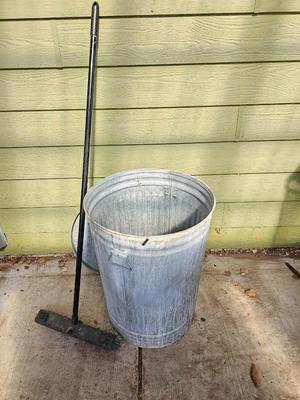 Galvanized metal trash can with lid and a push broom