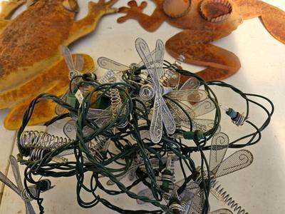Four metal garden frogs and a strand of dragonfly lights