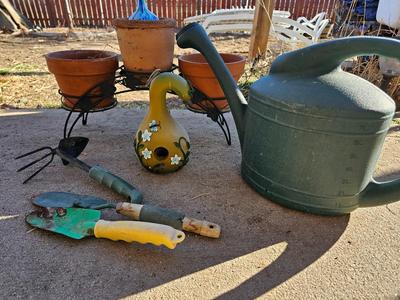 3 tiered plant stand with 3 terra cotta pots, small garden handtools, and watering can