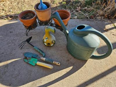 3 tiered plant stand with 3 terra cotta pots, small garden handtools, and watering can