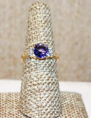 Size 7 Round Purple Stone Ring with Clear Stones Side Accents on a Gold Tone Band (2.4g)