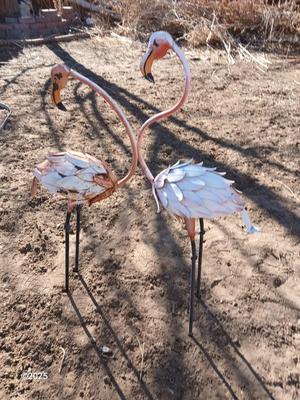 Two metal yard art flamingos