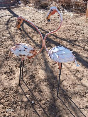Two metal yard art flamingos