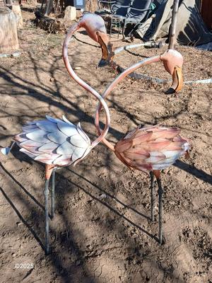 Two metal yard art flamingos