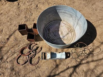 Galvanized tub with an assortment of horseshoes and metal boxes and an old can crsher