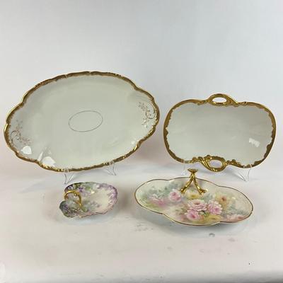 Sale Photo Thumbnail #458: White and gold serving dishes and two floral painted vanity dishes 
Large white plate is 11" x 9" 
White plate with handles is 11.5" x 6"