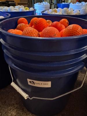 A bucket full of used Orange Golf Balls