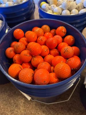 A bucket full of used Orange Golf Balls