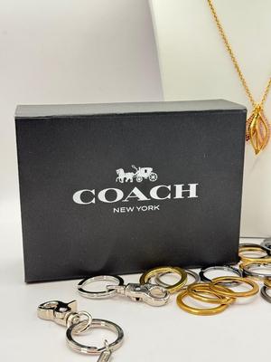 LOT 460J: 18” Coach Gold Tone Necklace, Coach Key Rings (18) & Gift Box
