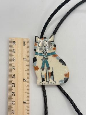 LOT 190J: Two Painted Clay Cat Bolo Ties
