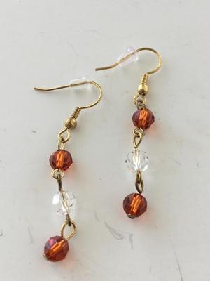 Gold tone clear and orange dangle earrings