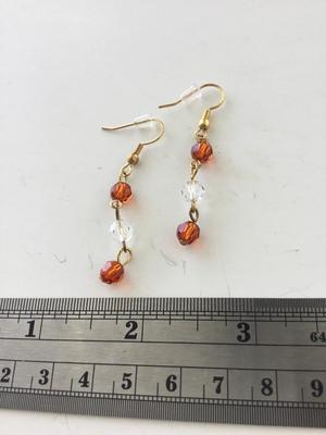 Gold tone clear and orange dangle earrings